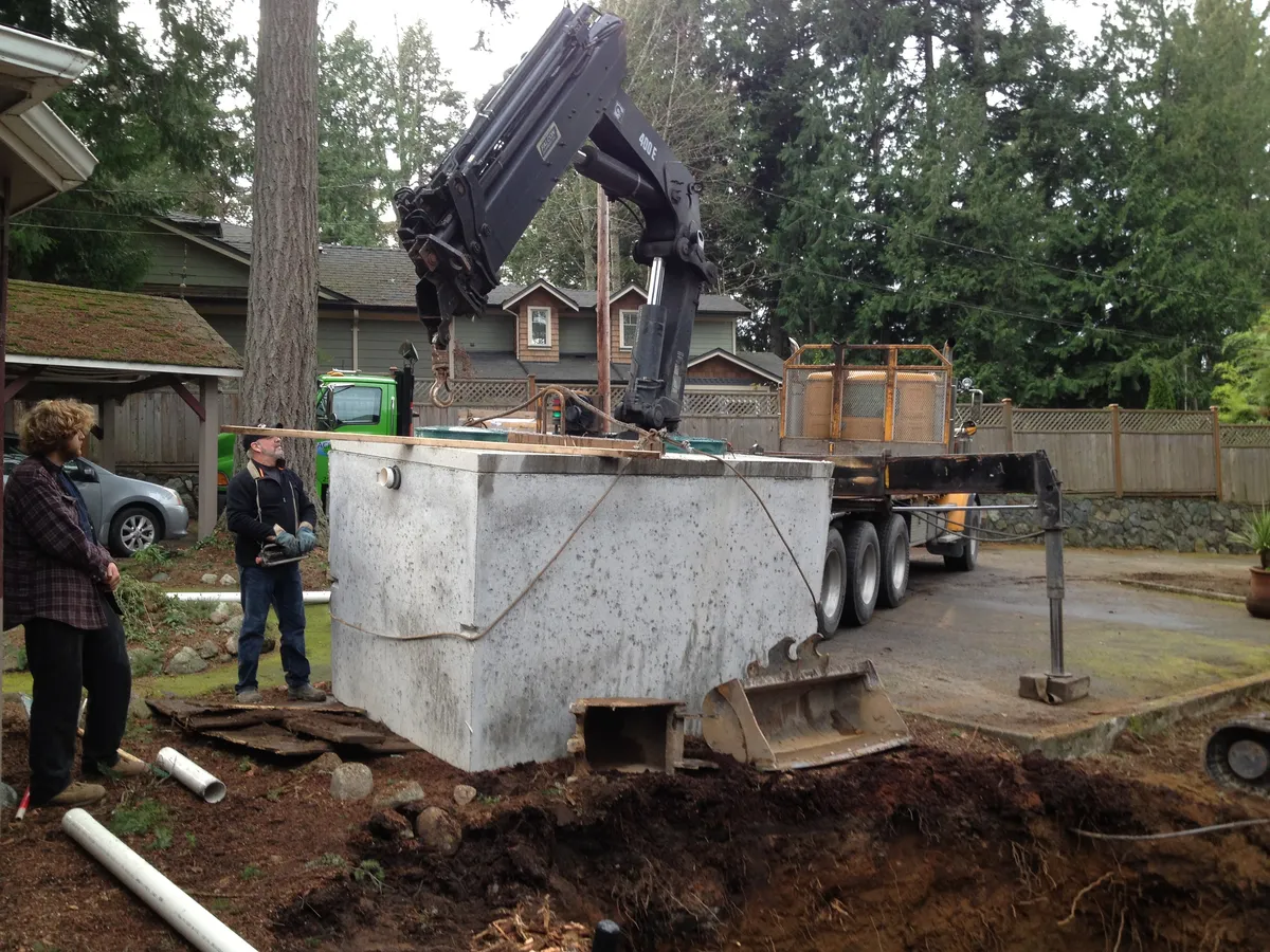 Heavy equipment installing large concrete septic tank