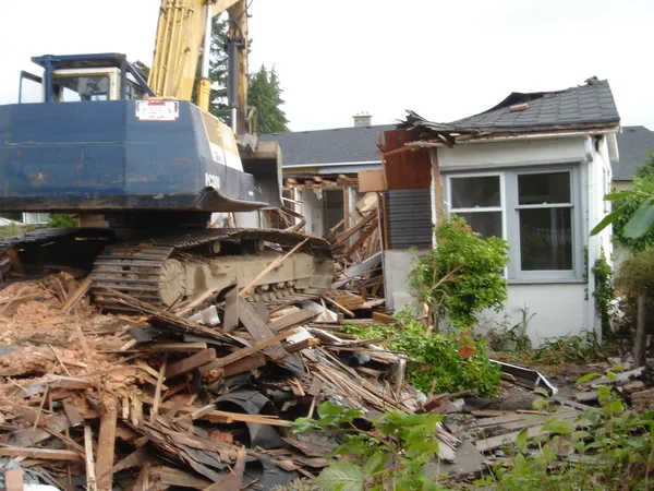 Excavator demolishing residential structure