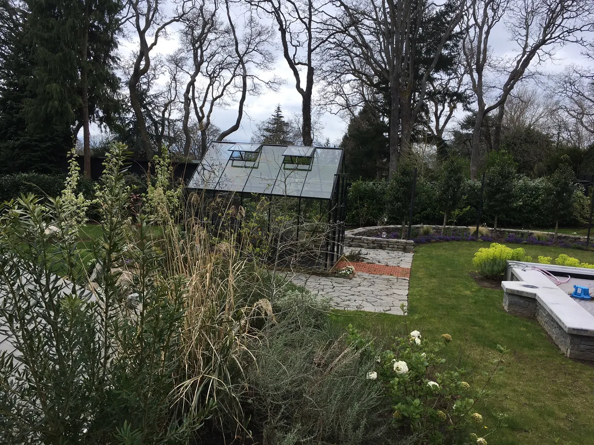 Custom greenhouse with retaining wall and pavers